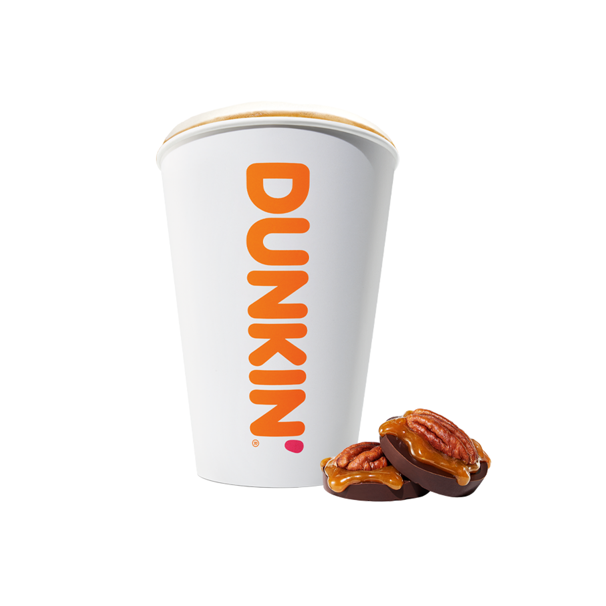 Ein weißer Kaffeebecher mit der Aufschrift "DUNKIN'" und zwei Pralinen mit Pekannüssen und Karamell daneben.